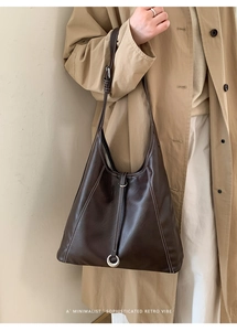Détails des surpiqûres blanches et anneau en argent sur un sac fourre-tout marron foncé
