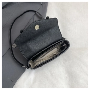 Interior detail of black litchi grain messenger bag with main compartment and zip pocket