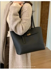 Close-up of black lychee leather tote bag with gold metal clasp on model's shoulder