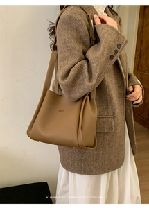 Detail view of brown lychee-pattern leather bucket bag with gold protective feet studs
