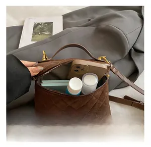Detailed interior of brown quilted crossbody bag showing storage capacity on a blazer