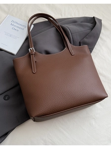 Detailed macro view of brown lychee-textured leather tote bag with silver buckle