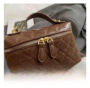 Detailed view of the brown quilted handbag featuring dual gold zippers and smooth leather trim