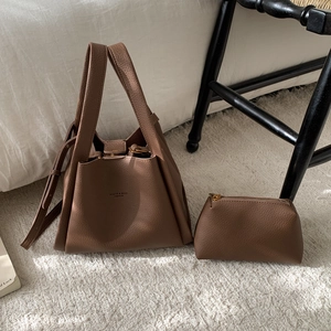 Detail of vintage brown textured leather bucket bag with matching inner pouch on a bed