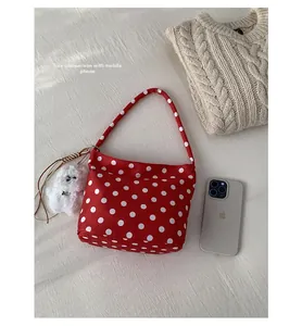 Detailed size comparison of the red polka dot shoulder bag next to a mobile phone