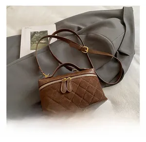 Macro detail of brown quilted suede handbag with gold zippers on a grey blazer suit