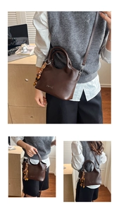 Detail view of deep brown leather tote with a vintage beaded tassel and metal logo