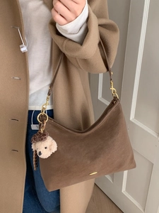 Deep brown suede hobo shoulder bag with a teddy bear pendant on a female model