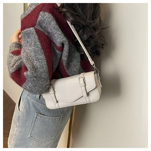 Detail of off-white lychee leather satchel with silver hardware and double strap buckle