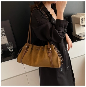 Detail of vintage pleated brown shoulder bag styled with a black coat on a model