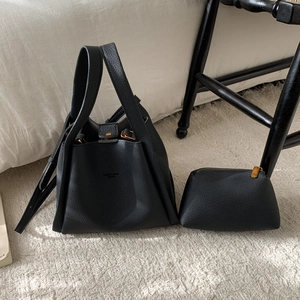 Detail of black lychee grain leather bucket bag set with matching inner pouch on rug