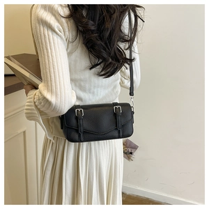 Close-up of black lychee grain leather crossbody bag with silver buckles and flap closure