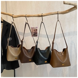 Présentation artistique de sacs seaux en cuir minimalistes en quatre couleurs sur branches