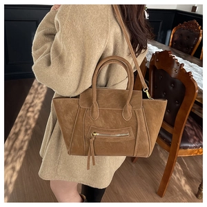 Detail einer matten braunen Henkeltasche im Vintage-Stil zum eleganten Wollmantel