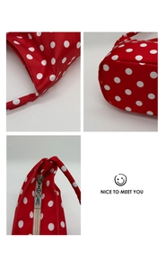 Macro detail of red polka dot canvas shoulder bag with silver zipper and strap stitching