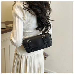 Detail of black lychee grain leather shoulder bag showing texture and buckle straps