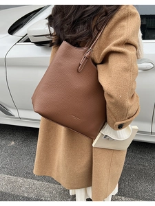 Close-up of brown pebble leather tote bag with contrast stitching and embossed logo detail