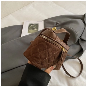 Detailed close-up of brown quilted square handbag with gold zippers and leather handle