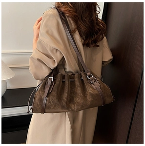 Detail view of brown suede underarm tote bag with drawstring closure and leather straps