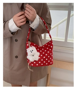 Sac à bandoulière rouge à pois avec pendentif chien en peluche porté par un mannequin