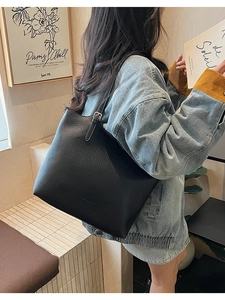 Close-up of black lychee grain leather tote bag with silver buckle worn on shoulder