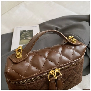 Detail of dark brown quilted leather handbag with gold zippers and suede base textures