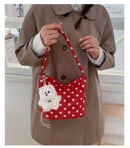Détail du sac hobo rouge à pois avec charmant chiot en peluche attaché à la bandoulière
