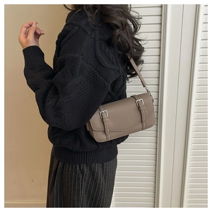 Close-up of brown lychee-patterned satchel bag worn with a black knitted sweater