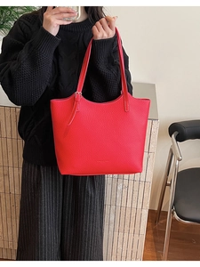 Detail of red lychee grain leather tote bag with adjustable shoulder strap and logo