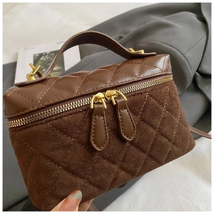 Close-up of brown quilted leather crossbody bag with dual gold zippers and sleek handle