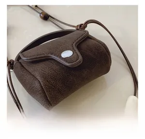 Detail of dark brown lychee texture leather mini bag with beaded strap and silver button