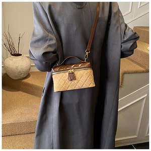 Detail of a quilted crossbody bag with brown suede finish and dual zipper closure on a model