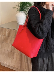 Detail of red pebbled leather tote bag with silver buckle on adjustable shoulder strap