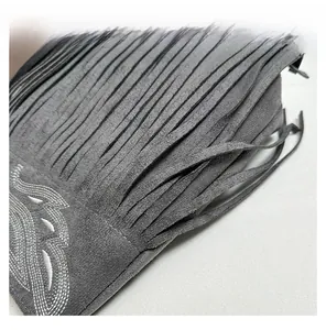 Detail view of the gray faux suede material with fringe tassels and embroidery patterns