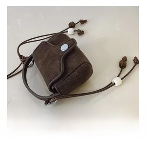 Detail of dark brown pebble leather mini crossbody bag with decorative beaded strap
