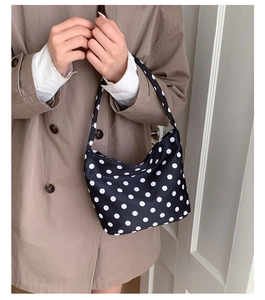 Detail of a black and white polka dot hobo bag with sleek canvas texture and shoulder strap