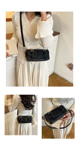 Detail of black lychee grain leather crossbody bag showing metal buckles and texture