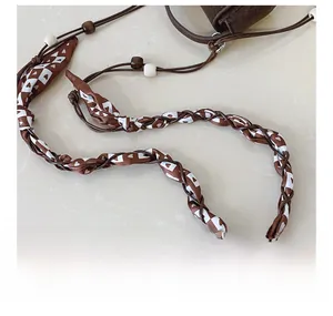 Detail of bohemian woven shoulder strap with heart patterns and brown wooden beads