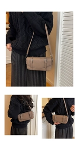 Detail of dark khaki litchi grain leather bag with dual silver buckle straps on the flap
