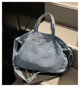 Détail du sac cabas en denim bleu avec rivets métalliques et bandoulière réglable