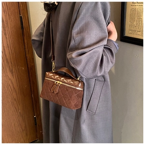Detail of vintage brown quilted crossbody bag with gold hardware and suede texture