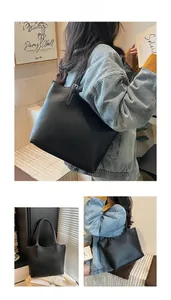 Detail view of large black lychee leather tote bag with adjustable shoulder strap and soft texture