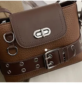 Détail macro du cuir grainé marron rétro et de la boucle argentée du sac à main