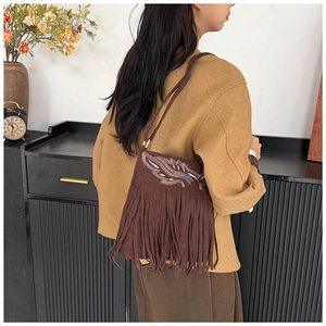 Detail of dark brown suede shoulder bag with white feather embroidery and long fringes