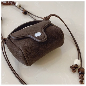 Detail of vintage suede mini crossbody bag with bead accents and silver buckle closure