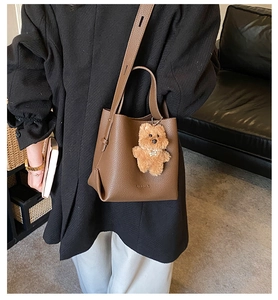 Detail view of dark brown litchi pattern bucket bag with cute plush bear charm