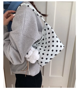 Detailed side view of polka dot shoulder bag with cute plush rabbit charm accessory