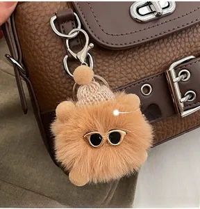 Gros plan d'un pendentif ours en peluche avec bonnet et lunettes sur un sac en cuir