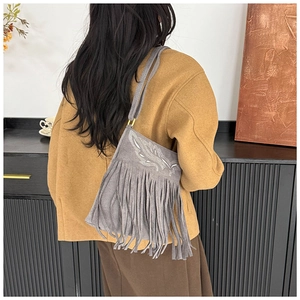Detailed shot of grey suede crossbody bag with leaf embroidery and bohemian fringes