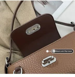 Détail du fermoir rotatif argenté sur le sac bandoulière en cuir grainé marron